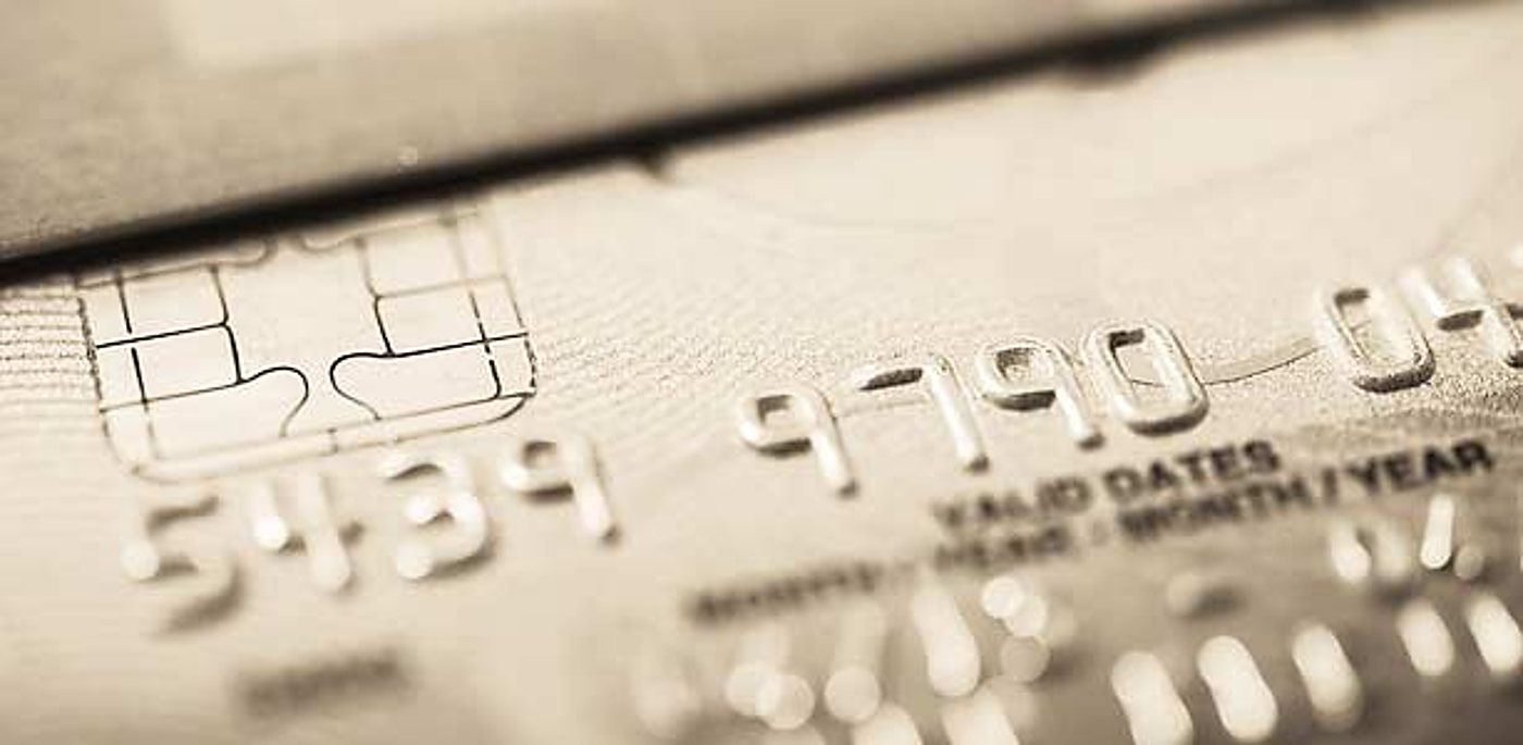 Gros plan en teinte sépia sur une carte bancaire montrant la puce électronique et des numéros embossés.